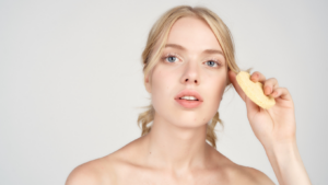 Young blonde woman holding sponge to face
