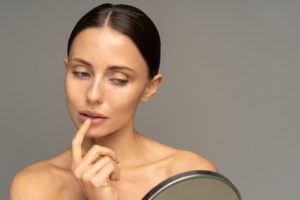 woman with mirror wondering when is the best time to get laser treatment