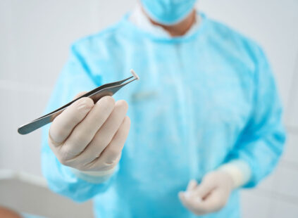 doctor in scrubs holding hormone pellet